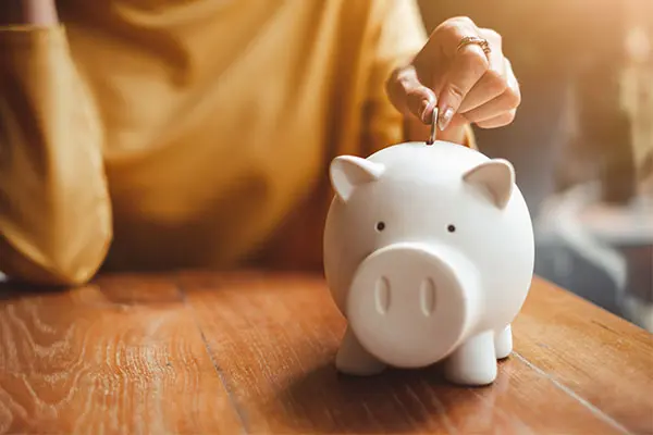 A woman putting a coin in a piggy bank