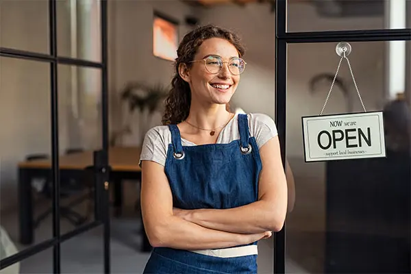 Woman standing by a sign that says her business is 'Open'